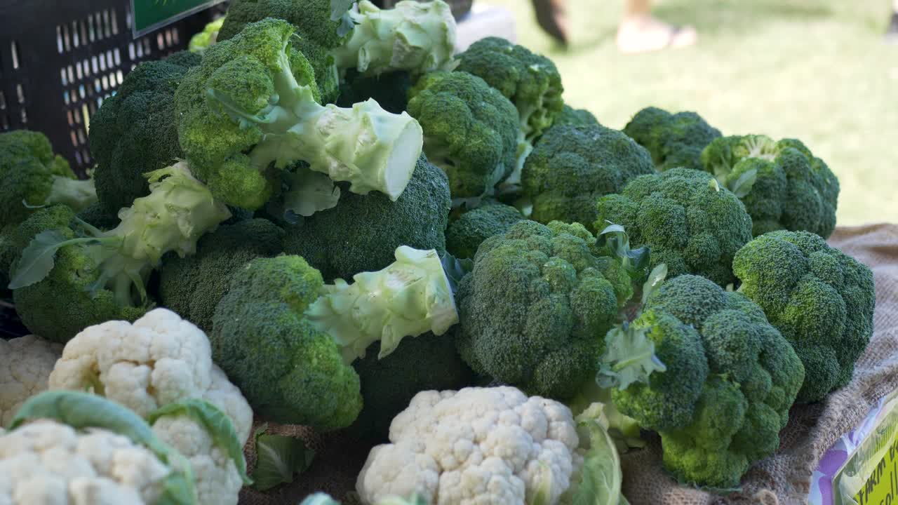 Slow motion close up of fresh broccoli and organic cauliflower vegetables displayed at a local farmers market stall on the Central Coast Australia food produce ingredients and agriculture