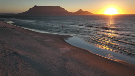 Kapstadt,-Südafrika,-Windsurfer,-Segeln,-Windig,-Brandung,-Welle,-Tafelberg,-Drohne,-Luftbild,-Filmisch,-Löwenkopf,-Sonnenuntergang,-Strand,-Atemberaubende-Berg--Und-Meereslandschaft,-Orangefarbenes-Gold,-Sonne,-Horizont,-Nach-Oben-Schwenken