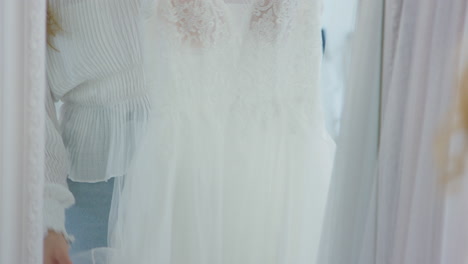 woman choosing  wedding dress in bridal store looking in mirror