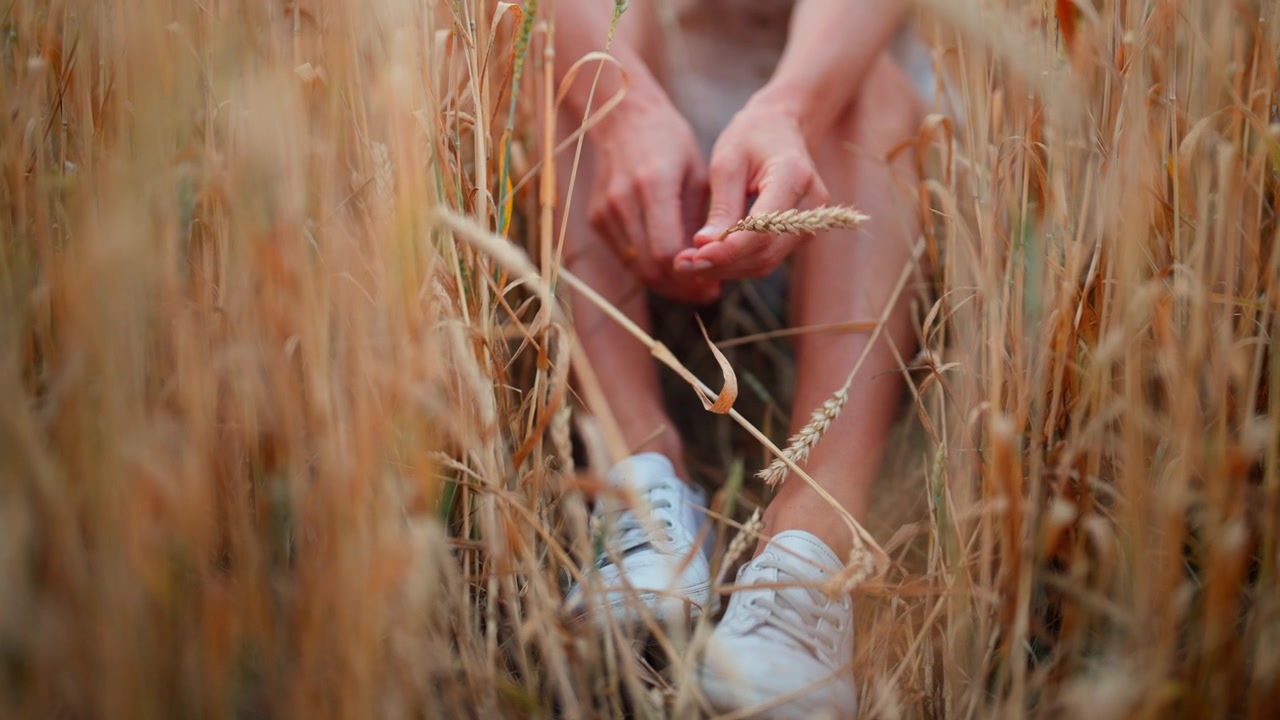 Woman Sitting in Wheat Field Holding Grain