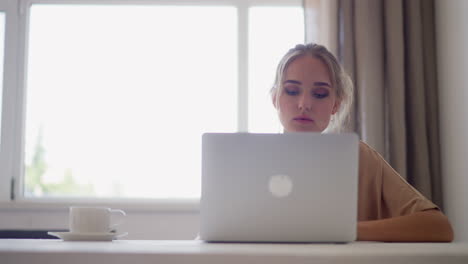 young woman freelancer works on laptop at home office