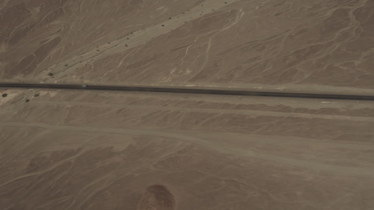 Aerial of road over Nasca valley desert with cars
