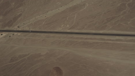 aerial of road over nasca valley desert with cars