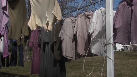 colorful shirts and dark dresses hand on a clothesline to dry near a large country home