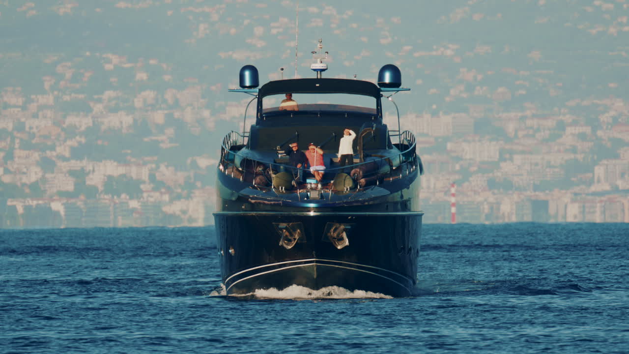Cannes, France - October 16, 2025: Elegant black yacht sailing across calm sea with a scenic coastal city backdrop