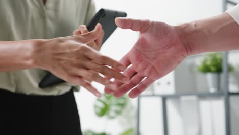 multiracial group of young creative people in smart casual wear discussing business shaking hands together and smiling while sitting in modern office.