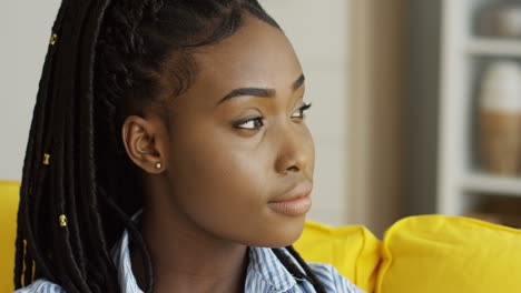 close up of the pretty young woman with a tail of pigtails looking and posing to the camera on the yellow sofa