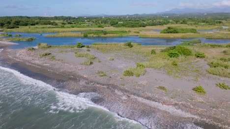 aerial view of river mouth of rio nizao surrounded by sea,rocky field and green landscape in backdrop