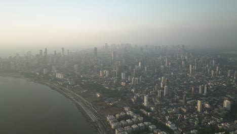 aerial pullback of mumbai sprawling skyline from marine drive on foggy morning, india