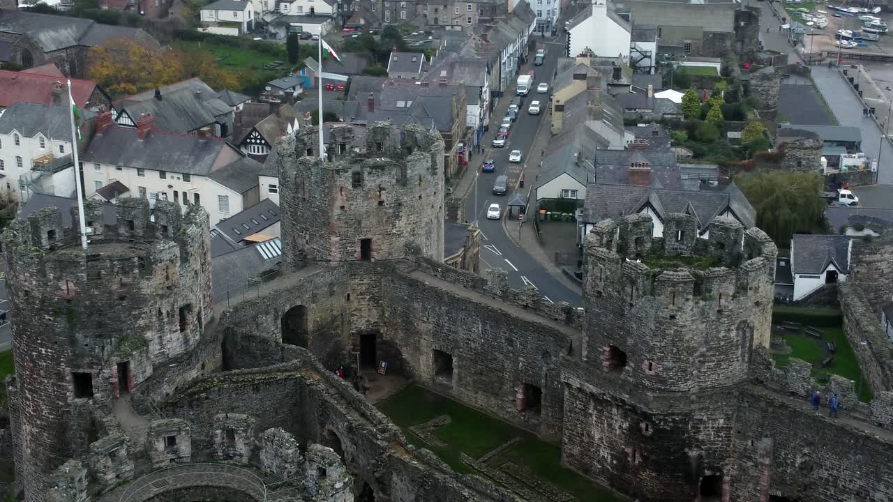 Vista aerea a volo d'uccello del Castello storico di Conwy, attrazione turistica con merlature di mura in pietra di un'antica città in rovina, con allontanamento a sinistra.