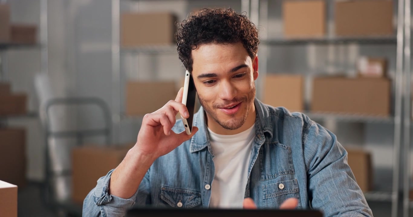 Young Man Talking on Smartphone in Warehouse Office