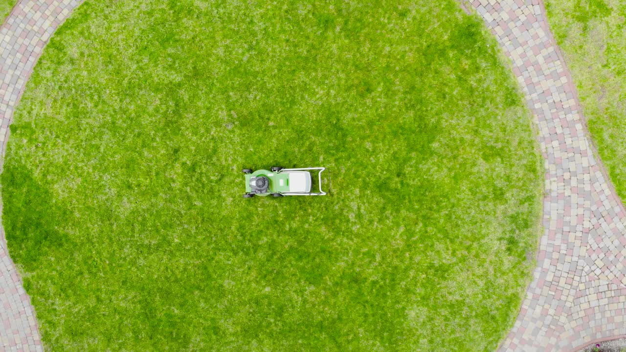 야드에서 신선한 잔디의 원에 녹색 잔디 기기의 드론 시각. 잔디를 자르는 도구.