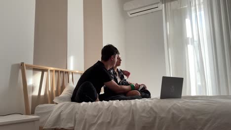 una pareja viendo una computadora portátil en la cama.