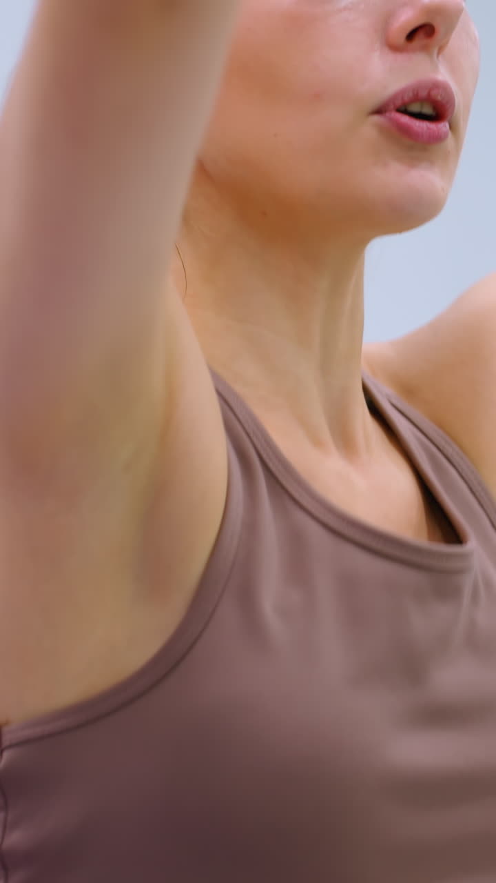 primer plano de mujeres participando en una sesión de fitness, estirando bandas de resistencia por encima de sus cabezas en un gimnasio bien iluminado, conversando y manteniendo la concentración en su rutina de ejercicio