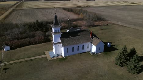 Drone-Acercándose-A-La-Hermosa-Y-Antigua-Iglesia-Del-Patrimonio-Sentada-Aislada-En-El-Paisaje-De-Las-Praderas-De-América-Del-Norte-En-Una-Soleada-Tarde-De-Otoño