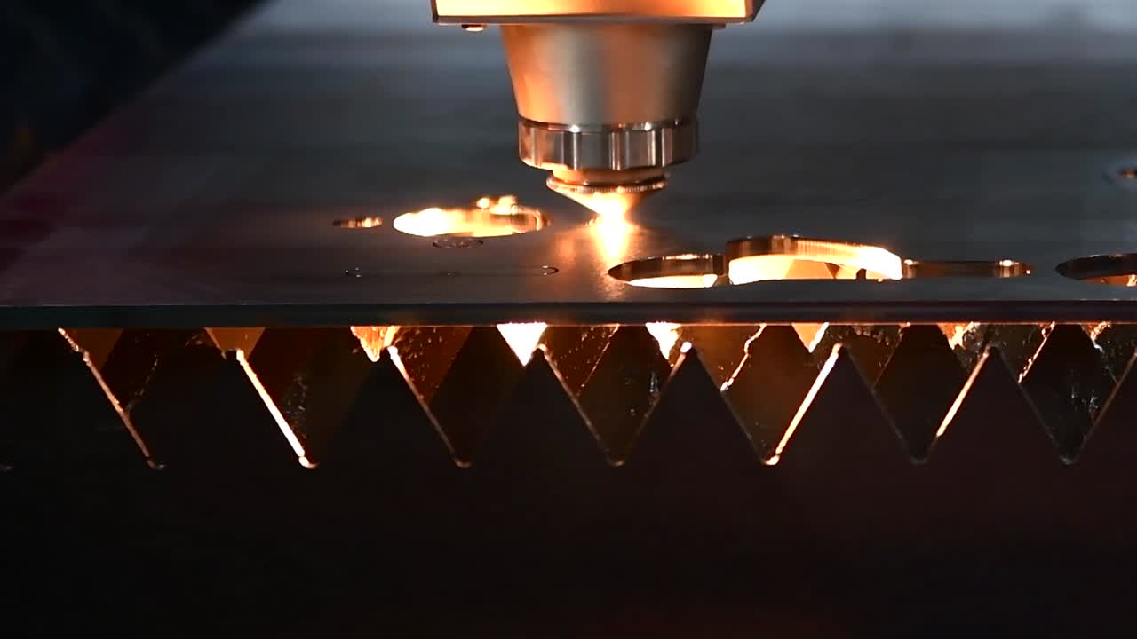 Macchina per il taglio laser industriale durante il taglio della lamiera con la luce scintillante.