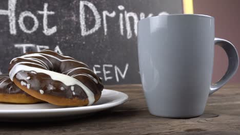 a cup of tea and donuts in chocolate glaze on a cafe table.