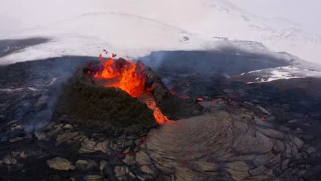 4k беспилотник, воздушный кинематографический, уникальные кадры изверженного вулканического пика быстро разливается лава и заснеженные зимние поля на заднем плане в исландии