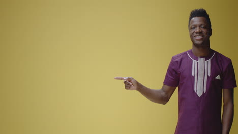 african man pointing to copy space on yellow background