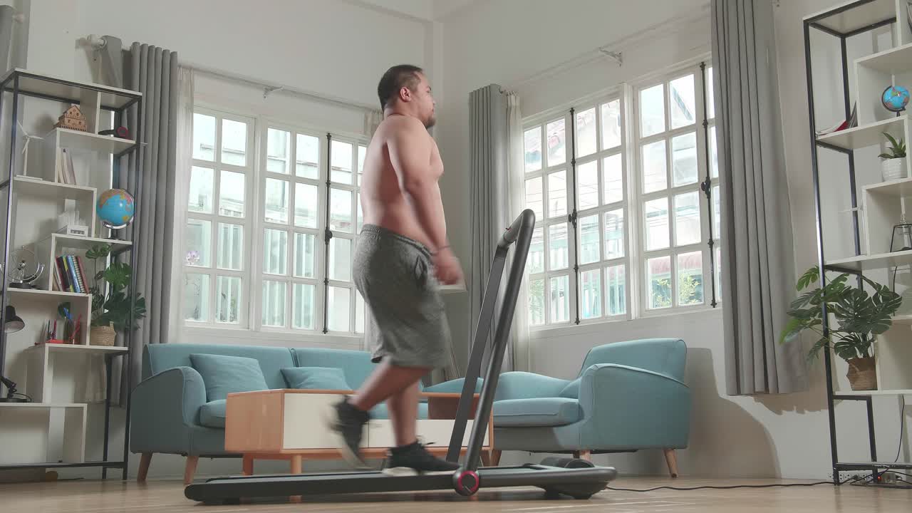 Asian Fat Man Wearing No T-Shirt Training On Walking Treadmill At Home