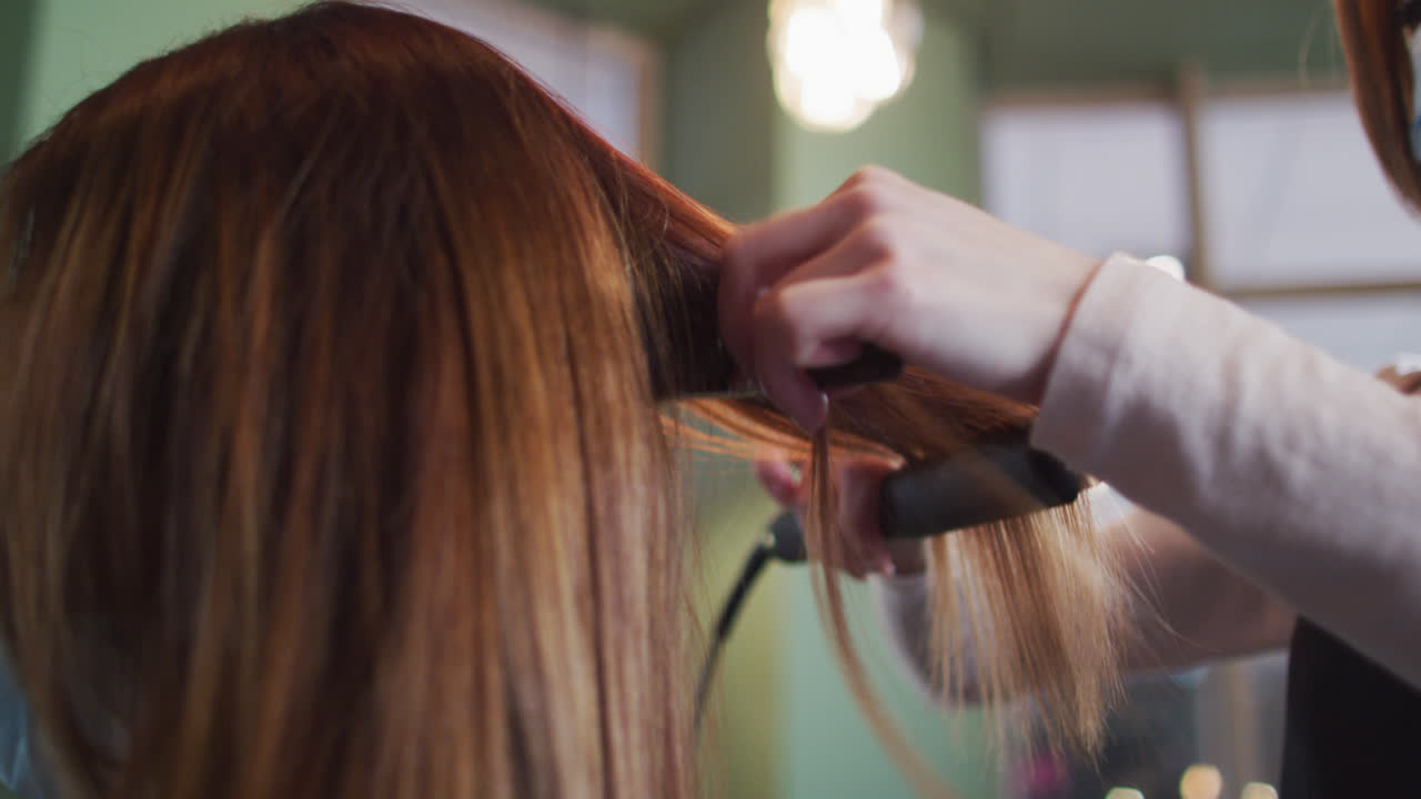 Parrucchiera che liscia i capelli di una cliente in un salone di bellezza.