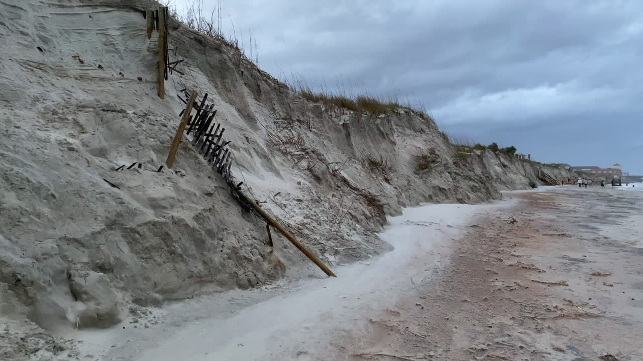 cerca destruida en la costa por la oleada de las olas del huracán y la erosión de las dunas de arena