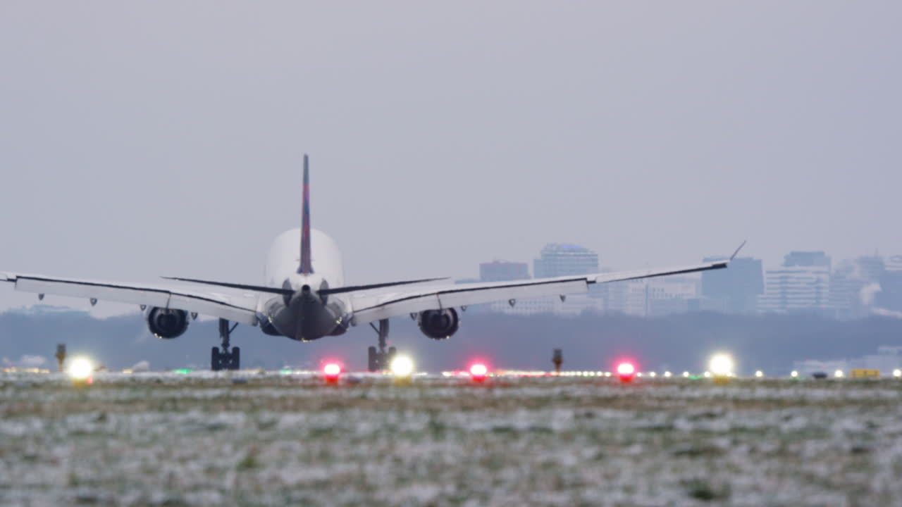 Aereo di linea di grandi dimensioni che atterra su una pista aeroportuale innevata.