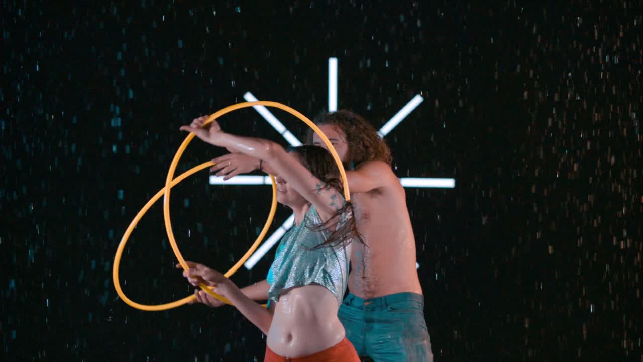Male and female hula hoopers, performing body workout visual effects in wet studio