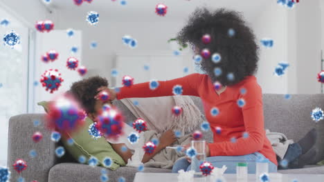 animation of coronavirus cells over biracial mother with face mask treating her son at home