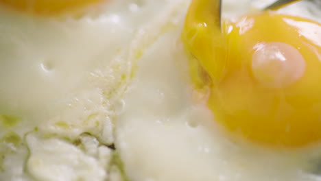 cutting a fried egg in pieces and lifting it up - slow motion, close up shot