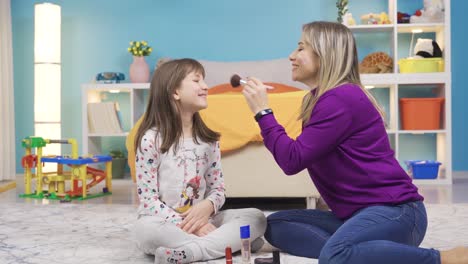 mom puts makeup on her curious little cute daughter. funny and cute girl.