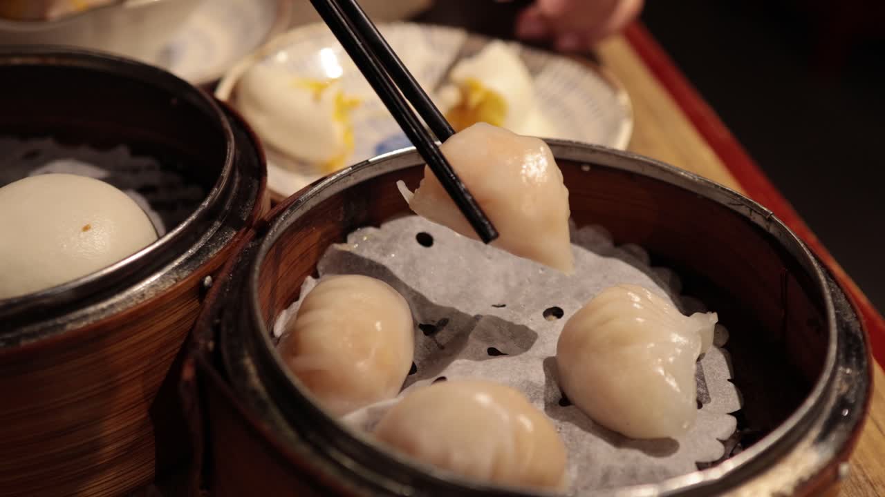 Chopsticks picking dumplings from a bamboo steamer