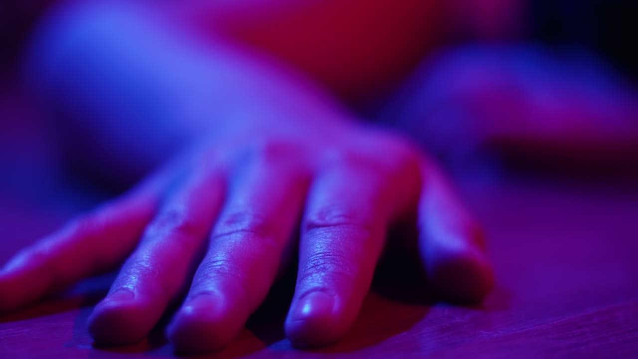 Primo piano di una mano su una superficie con luce al neon blu e rossa