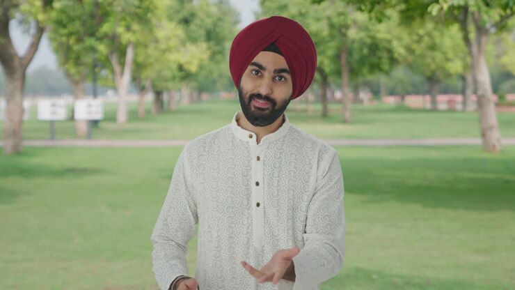 hombre indio sikh feliz hablando con la cámara en el parque