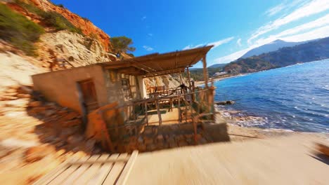 fpv aerial drone flying through a balcony and along a picturesque mediterranean beach along the coast of ibiza