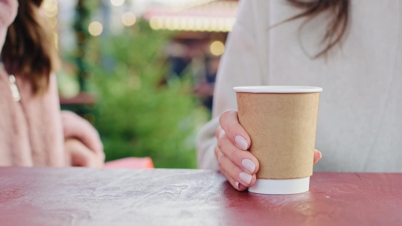 vista de mano de las mujeres bebiendo café sobre la mesa de madera