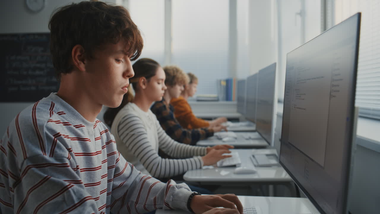 Close Up of Student in Striped Shirt Concentrating on Writing Code