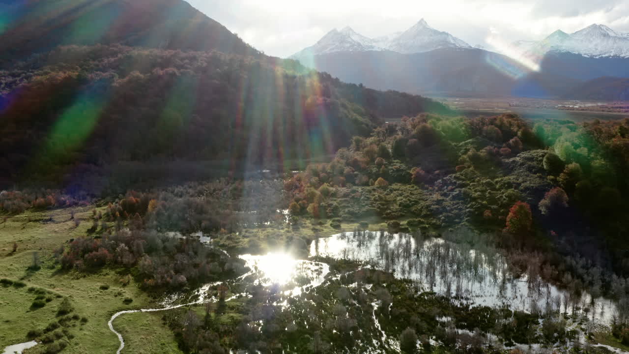 Sunrise over meandering river valley in Patagonia, Argentina, casting golden light on hills, aerial establishing