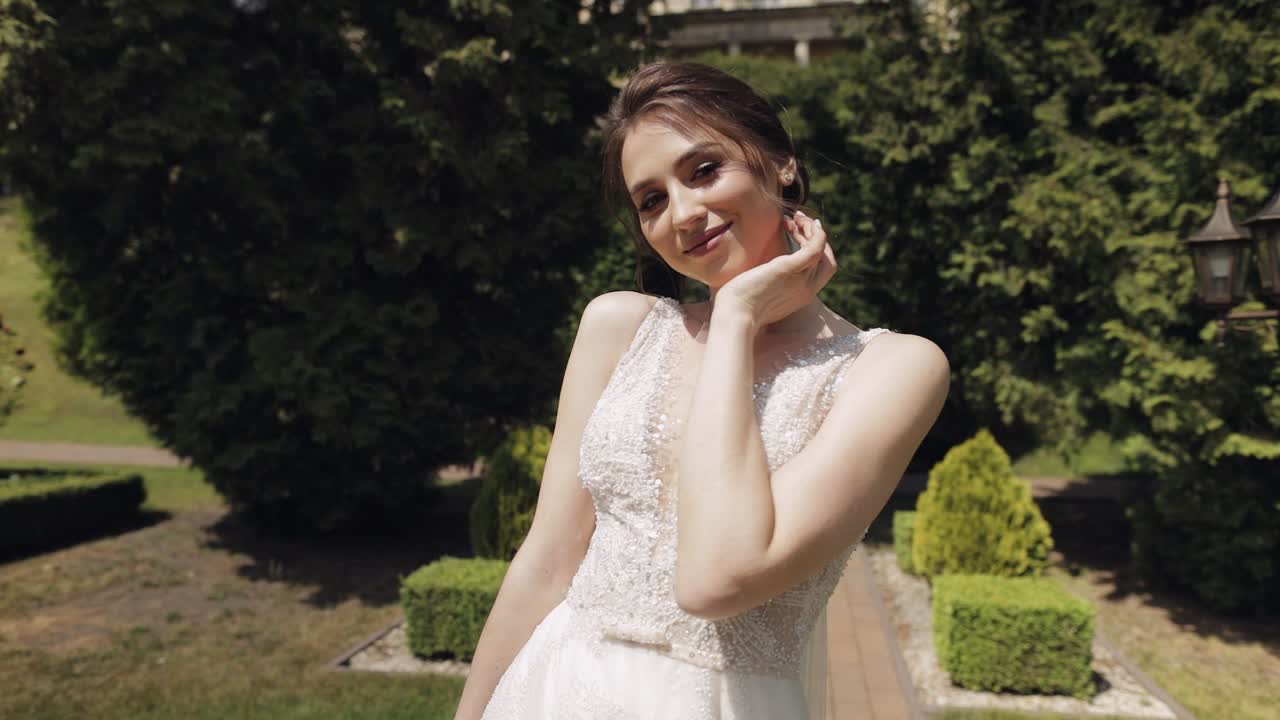 Sposa bellissima in abito bianco che sorride in un giardino.