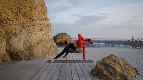 woman practicing yoga on a wooden deck overlooking the ocean