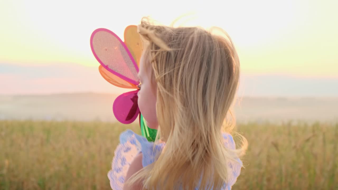 Little girl playing with a wind toy at sunset