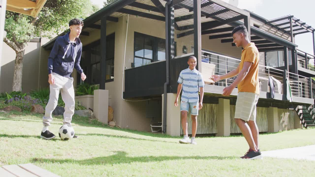 다양한 행복한 남성 십대 친구들이 정원에서 축구를 하고, 느린 움직임