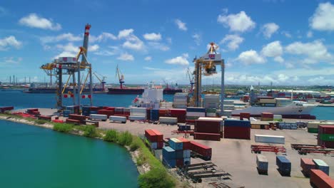 Puerto-De-Grúas-De-Contenedores-Con-Barco-Atracado,-Cielo-Azul-Día-Soleado-En-La-Isla-Caribeña-De-Curazao