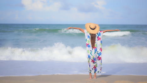 Asiatische-Frau,-Die-Am-Strand-Am-Meer-Steht-Und-Die-Hände-Hochhebt---Rückansicht-Der-Urlaubsvorlage