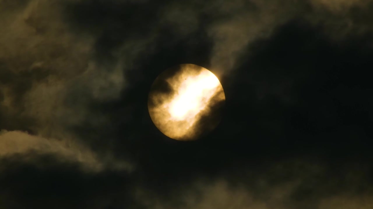 Close up, Yellow Full Moon behind fast moving dark clouds.