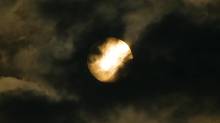 Close up, Yellow Full Moon behind fast moving dark clouds.