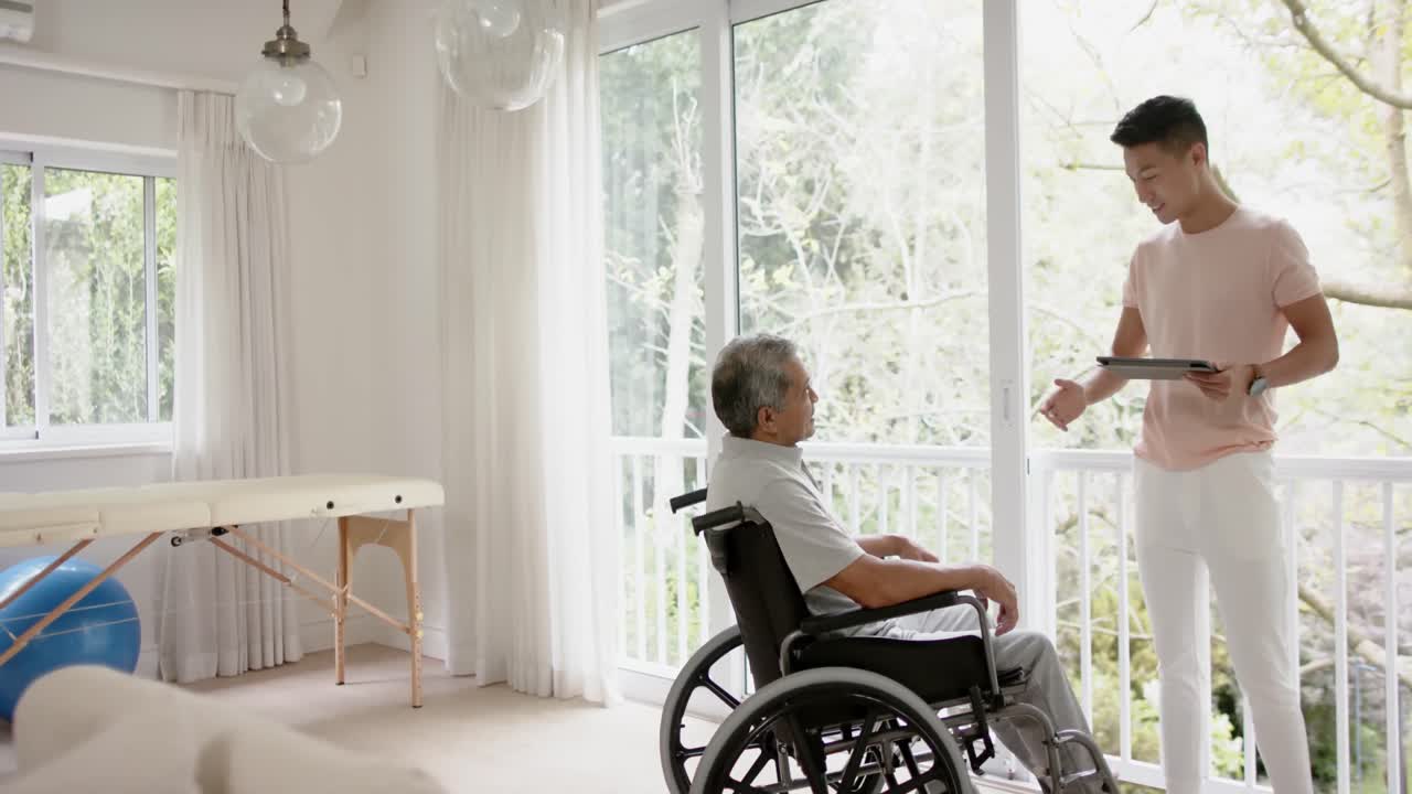 다양한 남성 물리치료사와 태블릿 조언과  ⁇ 체어에 앉은 노인, 슬로우모션