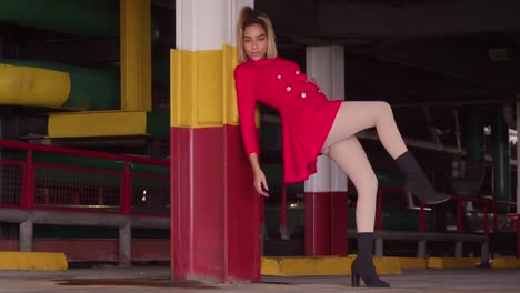 in the urban parking structure, a young girl of hispanic descent is adorned in a short red dress