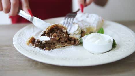 unrecognizable girl in red dress taking desert strudel at the restaurant using fork and knife. slow motion shot