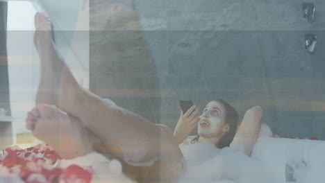 Using smartphone, woman with face mask relaxing in bubble bath, watching animation
